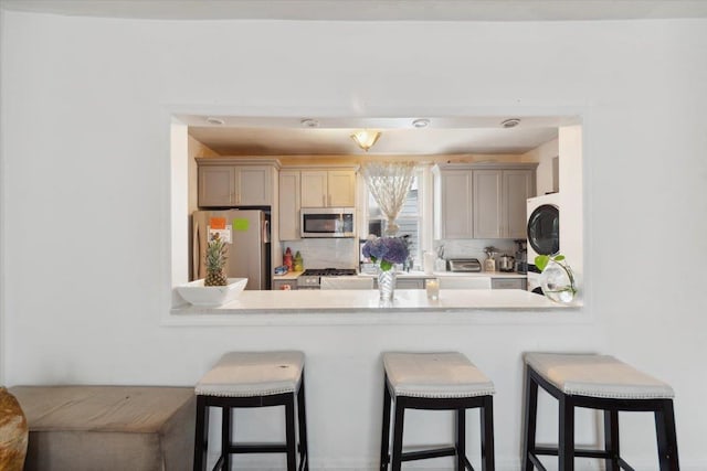 317 Hawthorne Ave, Yonkers, NY 10705 - kitchen featuring appliances with stainless steel finishes, a peninsula, a breakfast bar area, and backsplash