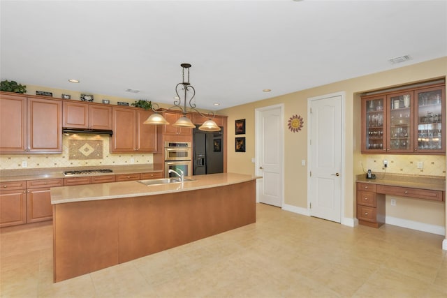 35 Monterrey Dr, Saint James, NY 11780 - kitchen with appliances with stainless steel finishes, backsplash, light countertops, a center island with sink, and brown cabinetry