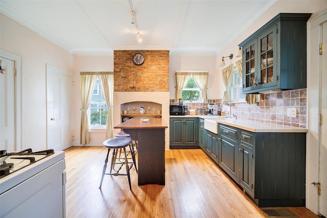 12 Beechwood Ter, Poughkeepsie, NY 12601 - kitchen featuring gas range gas stove, a kitchen breakfast bar, light wood-type flooring, decorative backsplash, and black microwave