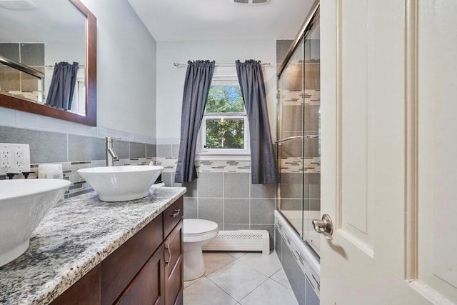 15 Stillwood Rd, Brookhaven, NY 11719 - full bathroom featuring a baseboard radiator, tile patterned flooring, double vanity, bath / shower combo with glass door, and tile walls