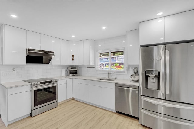 206 Friends Ln, Westbury, NY 11590 - kitchen featuring stainless steel appliances, modern cabinets, white cabinetry, ventilation hood, and light wood-type flooring