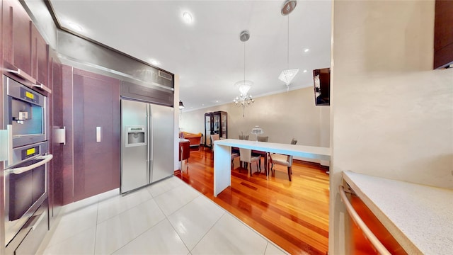 20 Corbin Pl, Brooklyn, NY 11235 - kitchen with stainless steel appliances, light tile patterned floors, hanging light fixtures, light countertops, and a chandelier