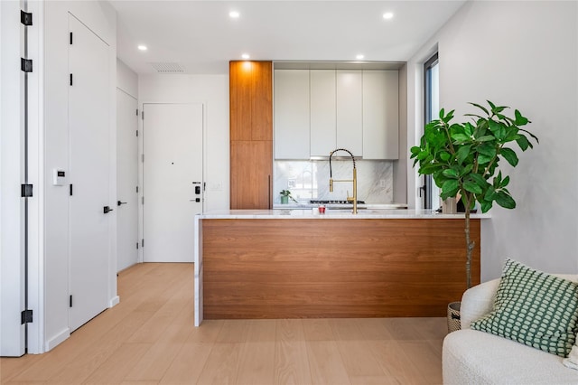 3116 21st St Unit Ph2F, Astoria, NY 11106 - kitchen with light countertops, backsplash, a peninsula, recessed lighting, and light wood-type flooring