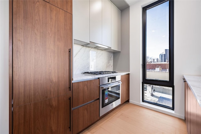 3116 21st St Unit Ph2F, Astoria, NY 11106 - kitchen with appliances with stainless steel finishes, tasteful backsplash, light countertops, and white cabinets