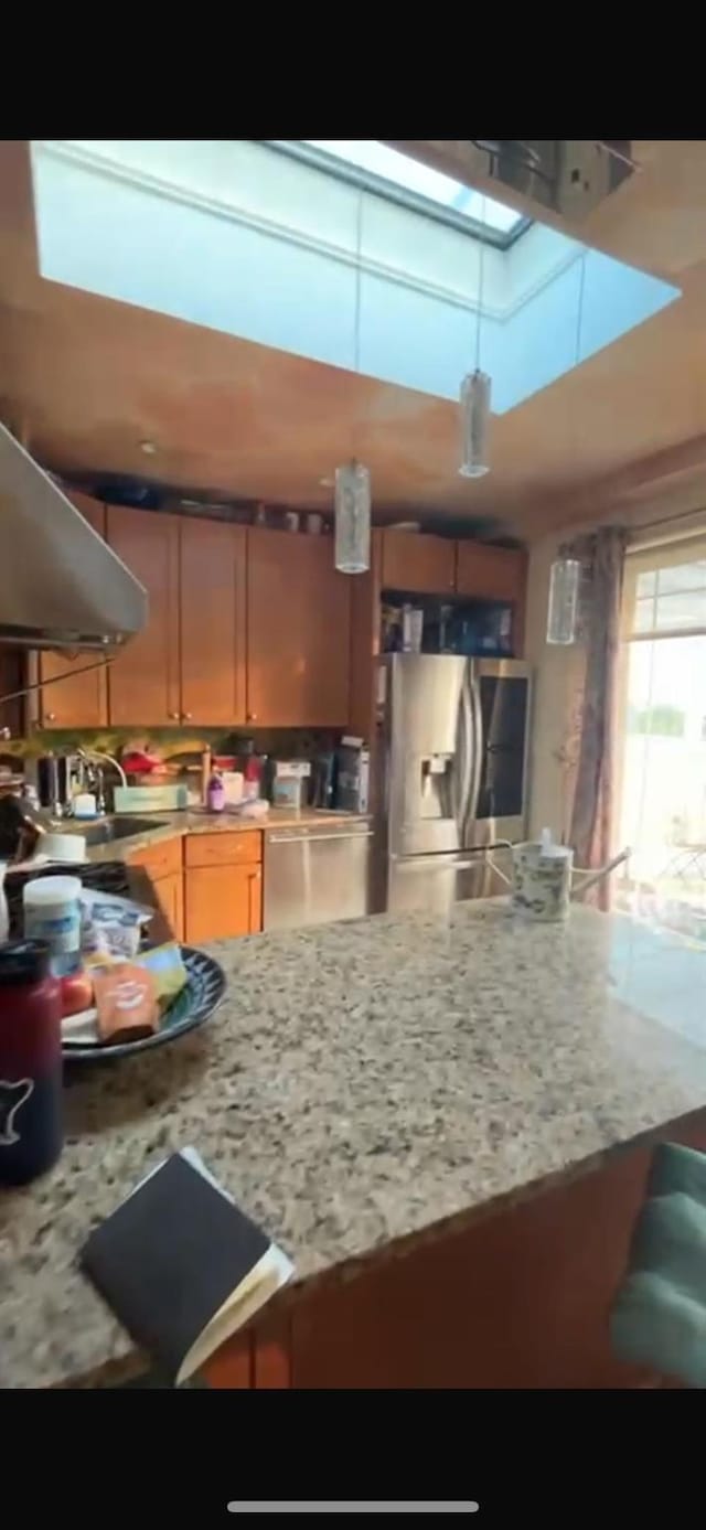 180 Bch 101st St Unit 3C, Rockaway Beach, NY 11694 - kitchen featuring stainless steel appliances, a skylight, wall chimney range hood, and light stone counters