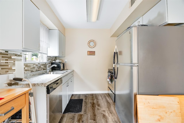 26 Cooper Rd Unit 416, Poughkeepsie, NY 12603 - kitchen featuring appliances with stainless steel finishes, light countertops, dark wood-style flooring, white cabinets, and backsplash