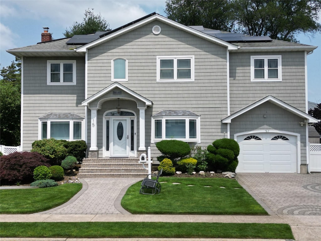 15 Cedar Dr E, Plainview, NY 11803 - view of front of house featuring solar panels, entry steps, a front lawn, and a garage