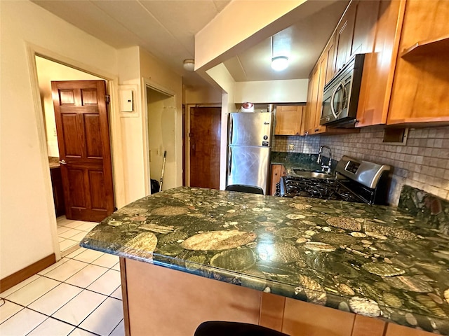 130-14 60th Ave Unit 2E, Flushing, NY 11355 - kitchen featuring appliances with stainless steel finishes, a peninsula, tasteful backsplash, light tile patterned floors, and dark stone countertops