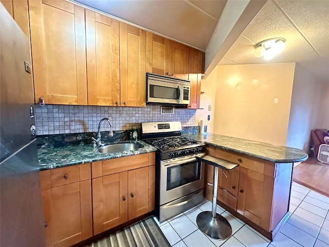 130-14 60th Ave Unit 2E, Flushing, NY 11355 - kitchen with appliances with stainless steel finishes, a peninsula, backsplash, light tile patterned floors, and dark stone countertops