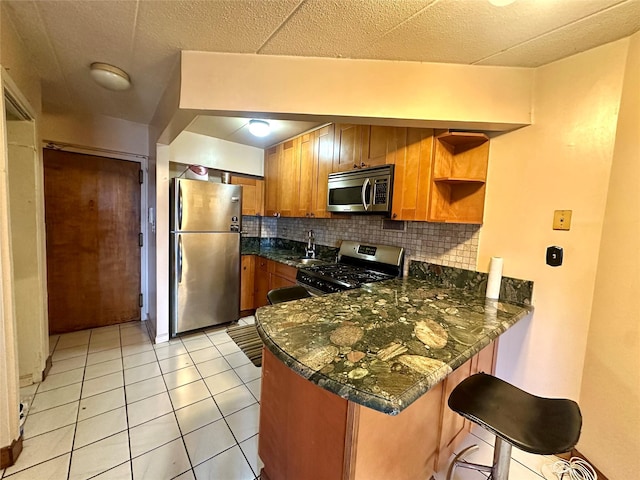 130-14 60th Ave Unit 2E, Flushing, NY 11355 - kitchen featuring appliances with stainless steel finishes, a peninsula, decorative backsplash, brown cabinets, and light tile patterned floors