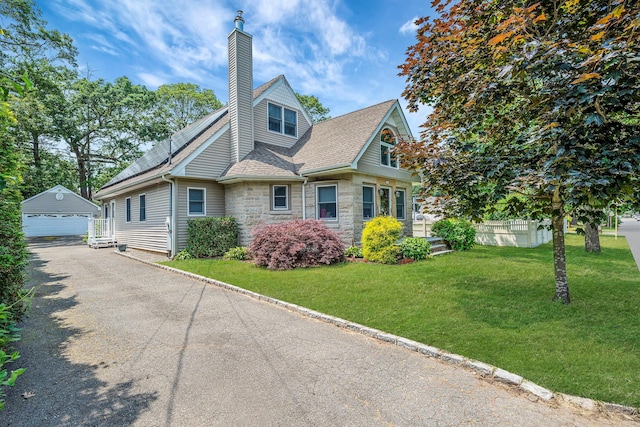 246 Cadman Ave, Babylon, NY 11702 - view of front of home with stone siding, an outdoor structure, a garage, a chimney, and a front lawn