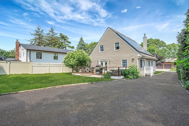 246 Cadman Ave, Babylon, NY 11702 - rear view of house featuring a chimney, a deck, roof mounted solar panels, and outdoor lounge area