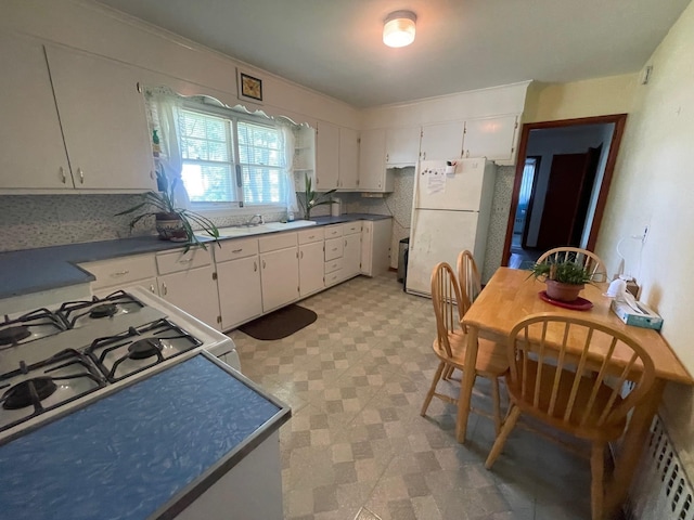 985 Ostrander Ave, Riverhead, NY 11901 - kitchen featuring white appliances, light flooring, white cabinetry, and dark countertops