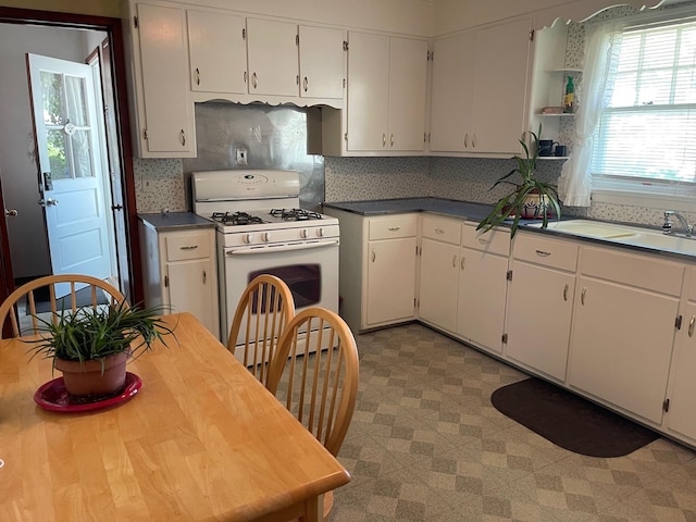 985 Ostrander Ave, Riverhead, NY 11901 - kitchen featuring gas range gas stove, white cabinets, light floors, open shelves, and decorative backsplash