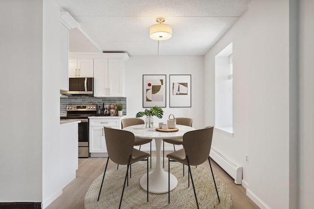 50 Columbus Ave Unit 611, Tuckahoe, NY 10707 - dining room featuring a baseboard heating unit, light wood-type flooring, and a textured ceiling