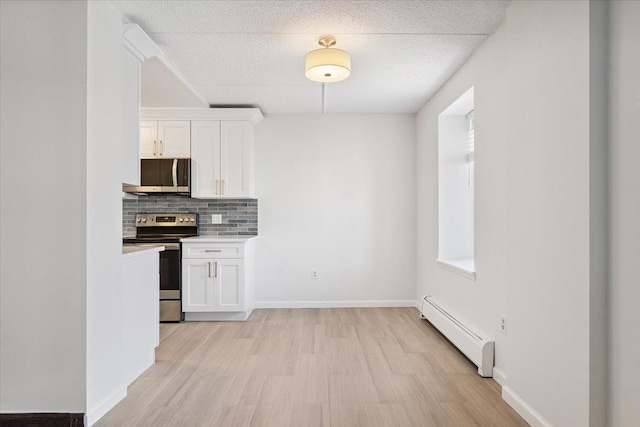 50 Columbus Ave Unit 611, Tuckahoe, NY 10707 - kitchen with appliances with stainless steel finishes, a baseboard radiator, backsplash, white cabinets, and light wood-style floors