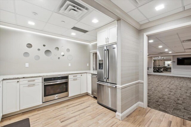 50 Columbus Ave Unit 611, Tuckahoe, NY 10707 - kitchen featuring stainless steel appliances, a paneled ceiling, white cabinetry, light stone countertops, and light wood-type flooring