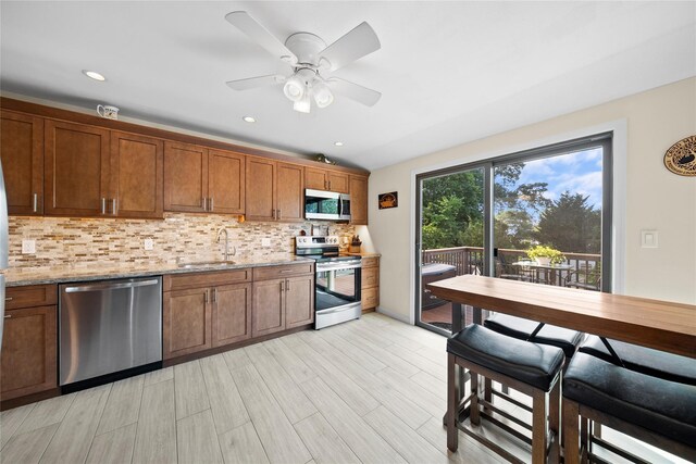 1583 5th St, West Babylon, NY 11704 - kitchen with appliances with stainless steel finishes, backsplash, brown cabinets, light stone countertops, and recessed lighting