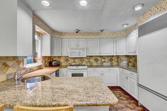 313 Pine St, Freeport, NY 11520 - kitchen with white appliances, light stone countertops, backsplash, a peninsula, and recessed lighting