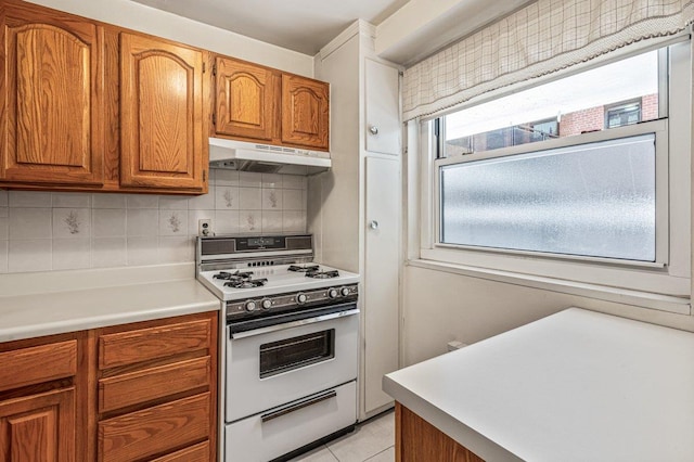 35-51 85th St Unit 2F, Jackson Heights, NY 11372 - kitchen featuring gas range gas stove, under cabinet range hood, brown cabinets, decorative backsplash, and light countertops
