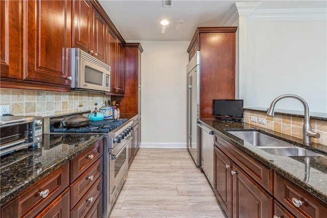 1 Christie Pl Unit 205E, Scarsdale, NY 10583 - kitchen with appliances with stainless steel finishes, dark stone countertops, decorative backsplash, ornamental molding, and light wood-style flooring