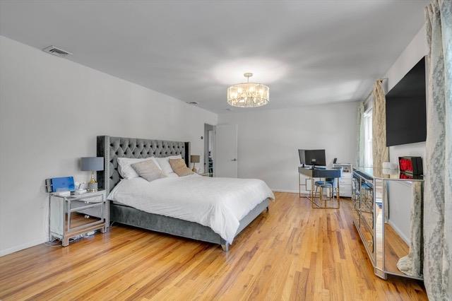 94 Fairview Ave, Great Neck, NY 11023 - bedroom with a chandelier, light wood-type flooring, and a desk