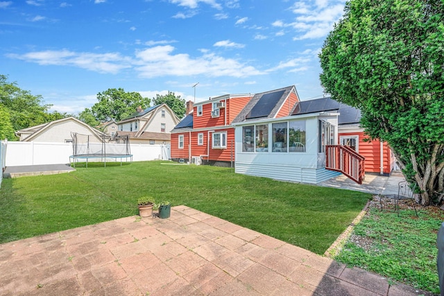 694 Koelbel Ct, Baldwin, NY 11510 - back of house with a trampoline, a patio, solar panels, entry steps, and roof with shingles