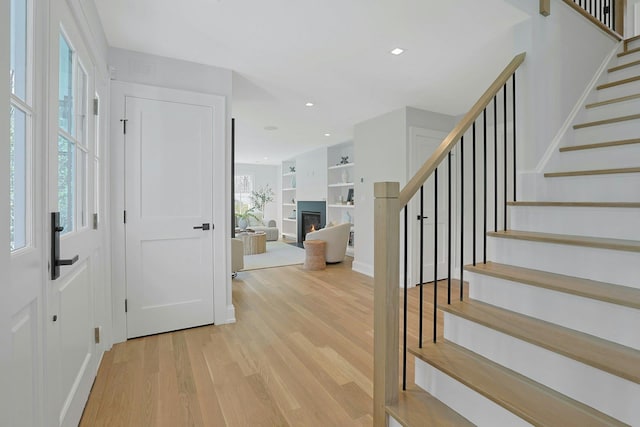 1 Devoe Rd, Armonk, NY 10504 - foyer entrance featuring light wood finished floors, stairs, a warm lit fireplace, and recessed lighting
