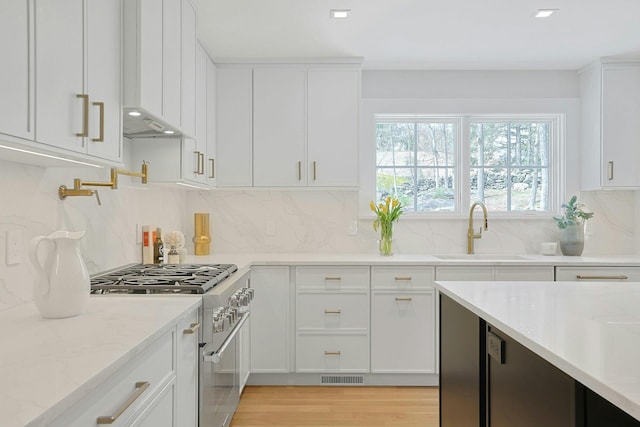 1 Devoe Rd, Armonk, NY 10504 - kitchen with stainless steel stove, white cabinetry, light wood finished floors, backsplash, and light stone countertops