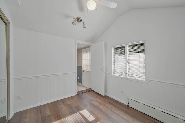 6 Sunrise Pl, Farmingville, NY 11738 - unfurnished room with a baseboard heating unit, wainscoting, wood finished floors, vaulted ceiling, and a ceiling fan