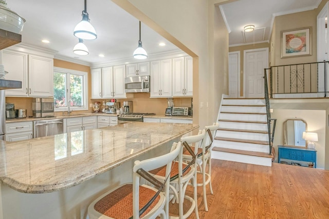 92 Wiltshire Rd, Scarsdale, NY 10583 - kitchen with stainless steel appliances, crown molding, white cabinetry, light stone countertops, and a breakfast bar area