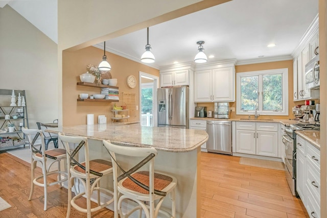 92 Wiltshire Rd, Scarsdale, NY 10583 - kitchen featuring appliances with stainless steel finishes, a peninsula, crown molding, light wood-style flooring, and white cabinetry