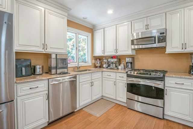 92 Wiltshire Rd, Scarsdale, NY 10583 - kitchen featuring appliances with stainless steel finishes, light wood finished floors, white cabinetry, ornamental molding, and recessed lighting