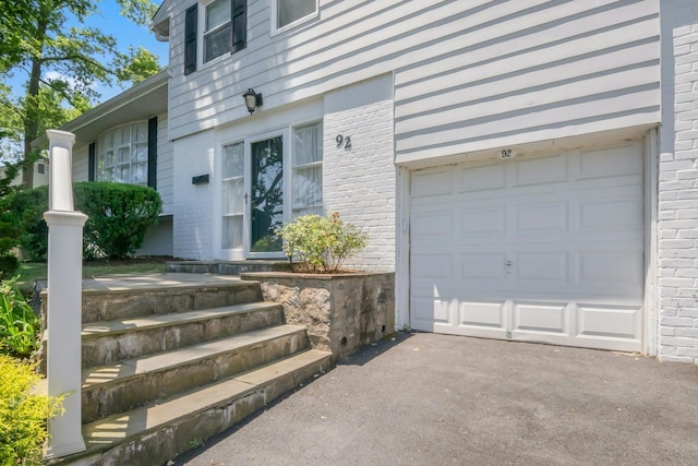 92 Wiltshire Rd, Scarsdale, NY 10583 - entrance to property with brick siding, a garage, and asphalt driveway