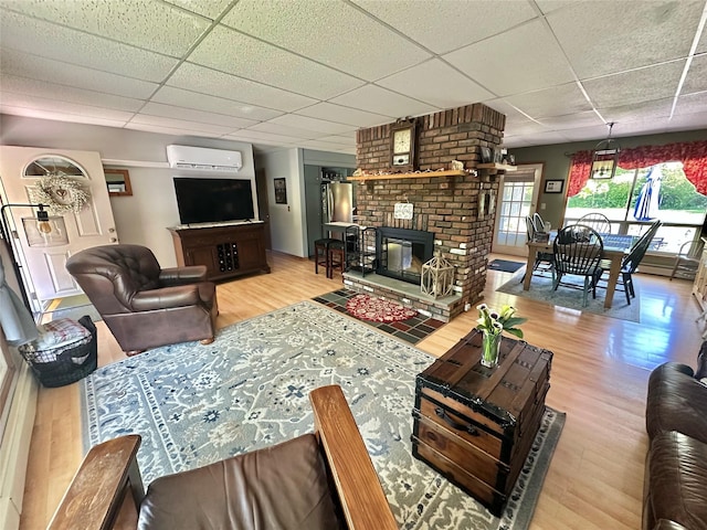 282 Petticoat Ln, Bloomingburg, NY 12721 - living room featuring wood finished floors, a drop ceiling, a wall mounted AC, and a fireplace