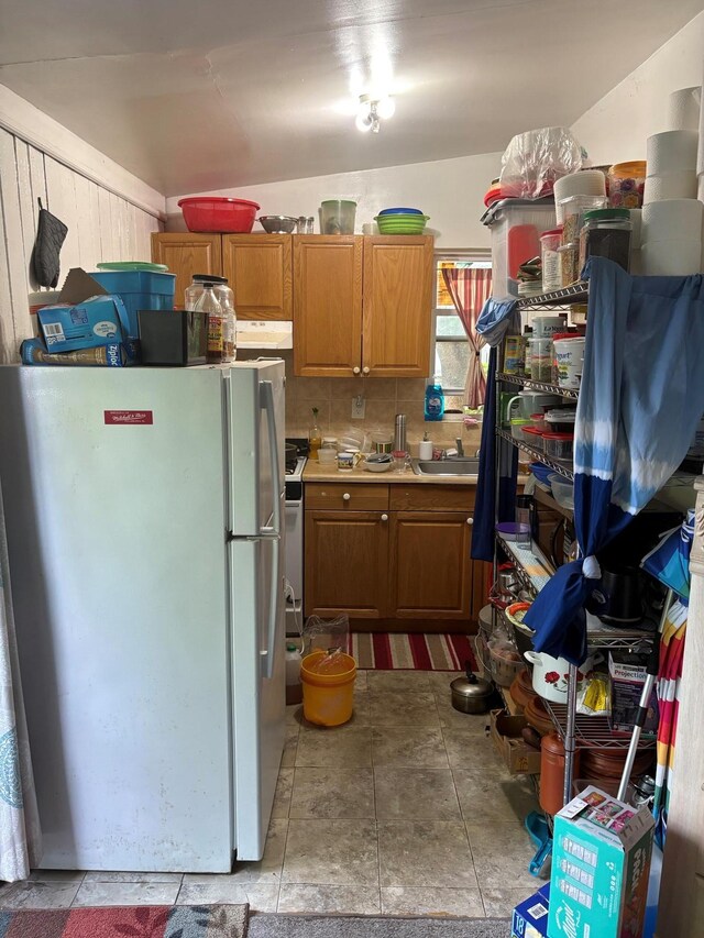 40 Samuel St, Ronkonkoma, NY 11779 - kitchen with freestanding refrigerator, under cabinet range hood, light countertops, brown cabinetry, and stone finish floors