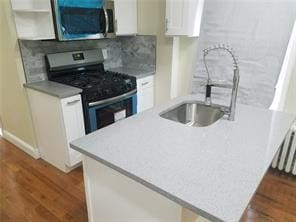 2718 Holland Ave, Bronx, NY 10467 - kitchen with appliances with stainless steel finishes, white cabinetry, wood finished floors, and light countertops