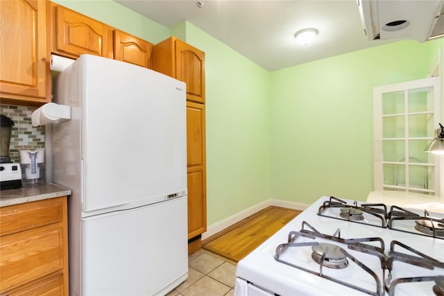 83-10 35th Ave Unit 5B, Jackson Heights, NY 11372 - kitchen featuring white appliances, backsplash, light tile patterned floors, a wood stove, and brown cabinets