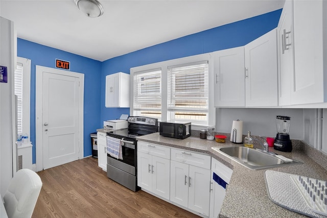 439 S 7th Ave, Mount Vernon, NY 10550 - kitchen with stainless steel range with electric stovetop, black microwave, white cabinetry, light wood-type flooring, and light countertops