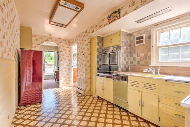 62 Port Washington Rd, Sound Beach, NY 11789 - kitchen featuring dishwashing machine, wallpapered walls, arched walkways, light flooring, and cream cabinets