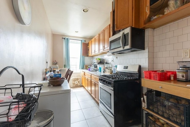 5836 Catalpa Ave, Ridgewood, NY 11385 - kitchen with appliances with stainless steel finishes, brown cabinetry, backsplash, light tile patterned floors, and light countertops