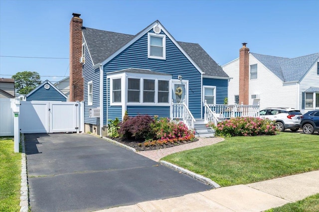 209 Venetian Blvd, Lindenhurst, NY 11757 - view of front of home featuring a gate, a shingled roof, a chimney, and a front lawn
