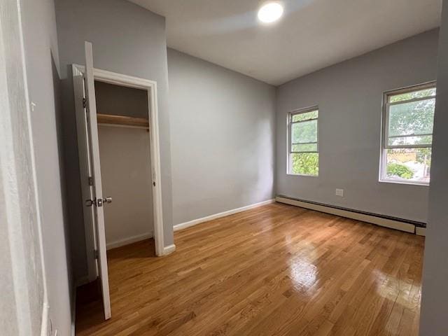 10326 171st St, Jamaica, NY 11433 - unfurnished bedroom featuring a baseboard heating unit, wood finished floors, and a closet