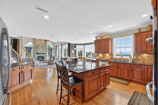 36 Ballymeade Rd, Hopewell Junction, NY 12533 - kitchen with light wood-type flooring, a breakfast bar area, a fireplace, healthy amount of natural light, and ornamental molding