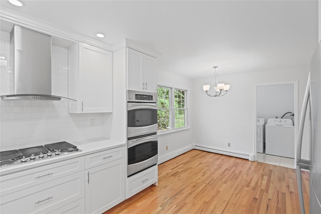 21 Kipp St, Chappaqua, NY 10514 - kitchen featuring appliances with stainless steel finishes, a baseboard heating unit, wall chimney range hood, washing machine and clothes dryer, and a chandelier