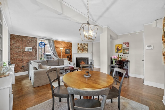 20 N Broadway Unit O-373, White Plains, NY 10601 - dining area with wood finished floors, a lit fireplace, crown molding, a chandelier, and brick wall