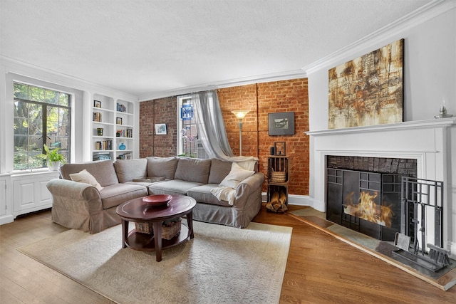 20 N Broadway Unit O-373, White Plains, NY 10601 - living area featuring a fireplace with flush hearth, wood finished floors, built in shelves, brick wall, and ornamental molding
