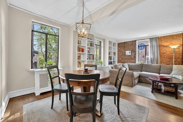 20 N Broadway Unit O-373, White Plains, NY 10601 - dining space with a chandelier, brick wall, ornamental molding, wood finished floors, and built in shelves