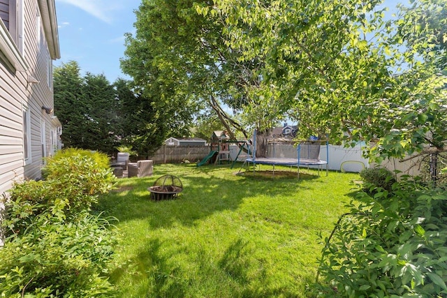 2691 Evans Rd, Oceanside, NY 11572 - fenced backyard with a trampoline, a playground, and a fire pit