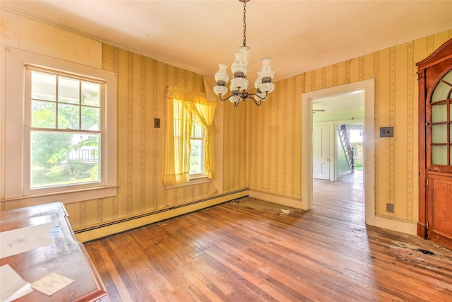 2 Shore Rd, East Setauket, NY 11733 - unfurnished dining area with a baseboard heating unit, wood-type flooring, a chandelier, crown molding, and wallpapered walls